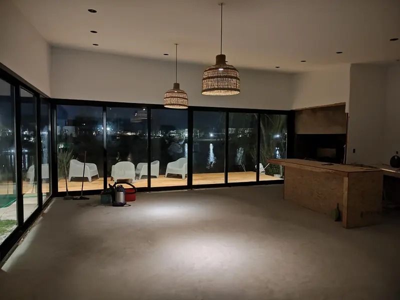 Interior de la ampliación con ventanales de piso a techo, de noche