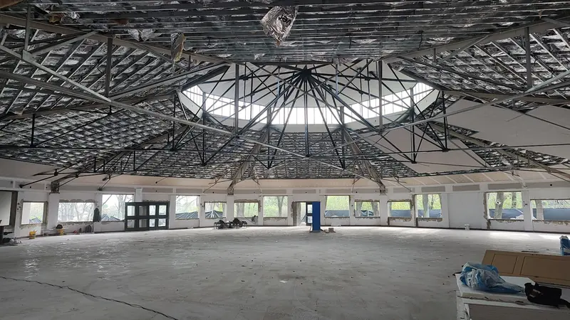 Interior del salón con la estructura metálica de la cubierta y la claraboya central, en obra